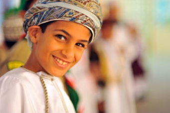 Oman, Muscat, close-up portrait of a cheerful boy in a turban smiling